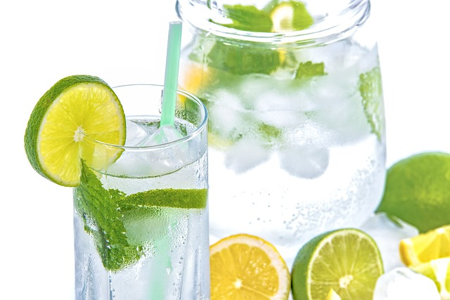 An image of a pitcher and glass of ice water with lime slices. 