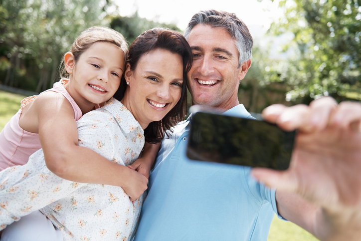 Cheerful family of three snapping a selfie in a park.