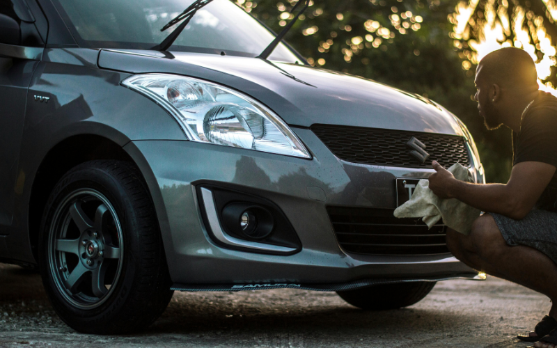 Person drying a silver car with a microfiber towel after washing the car