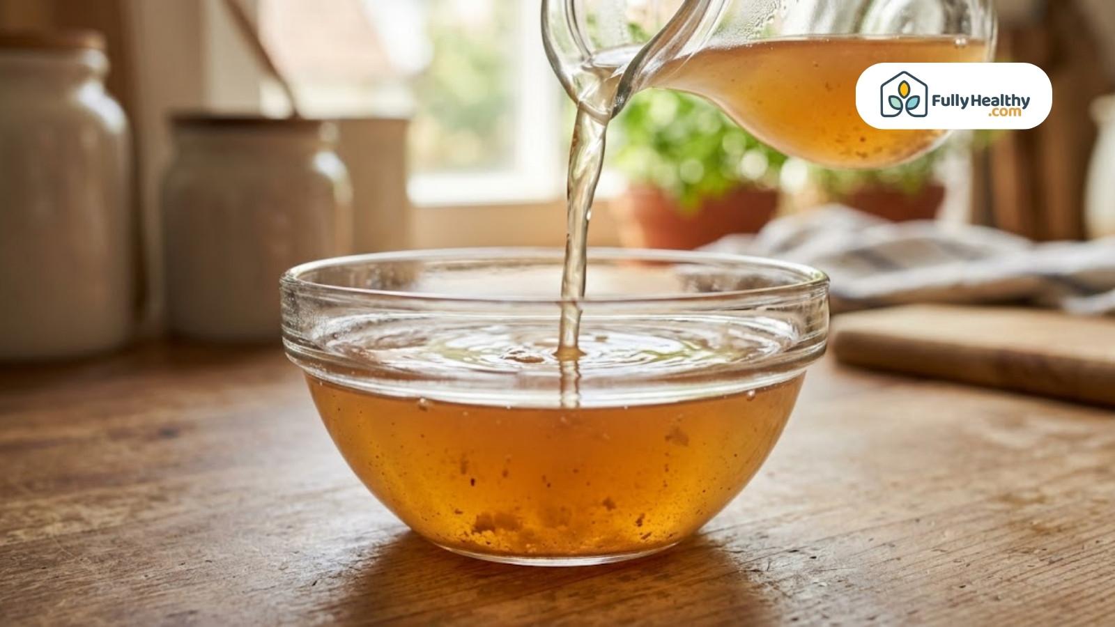 Apple cider vinegar being poured into glass bowl in bright kitchen