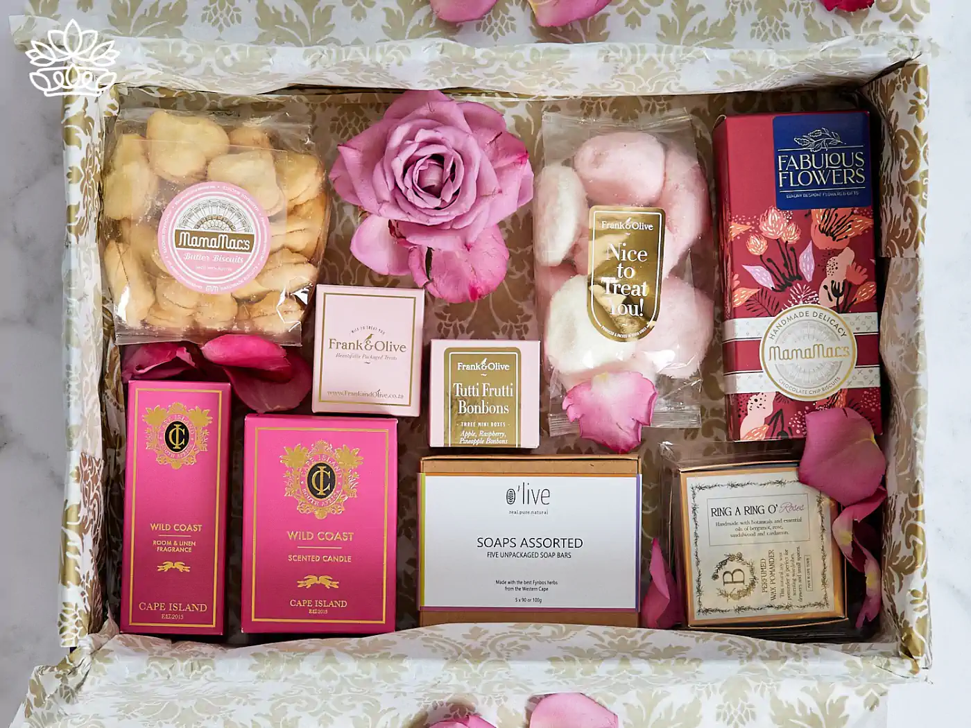Luxury get well gift box filled with assorted treats including butter biscuits, scented candles, room fragrance, and artisanal soaps, all elegantly displayed amongst fresh rose petals. Delivered with Heart. Fabulous Flowers and Gifts.