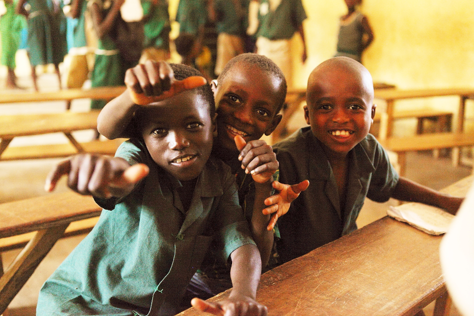 Portraitaufnahme dreier Jungen, die in einer Schule in Sierra Leone sitzen, in die Kamera strahlen und Daumen hoch zeigen. Wir zeigen dir, was du zum Thema Bildung in Sierra Leone wissen musst!