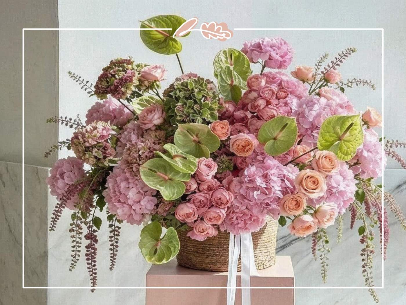 Close-up of a lush pink hydrangea and rose basket arrangement featuring green anthurium leaves and cascading foliage