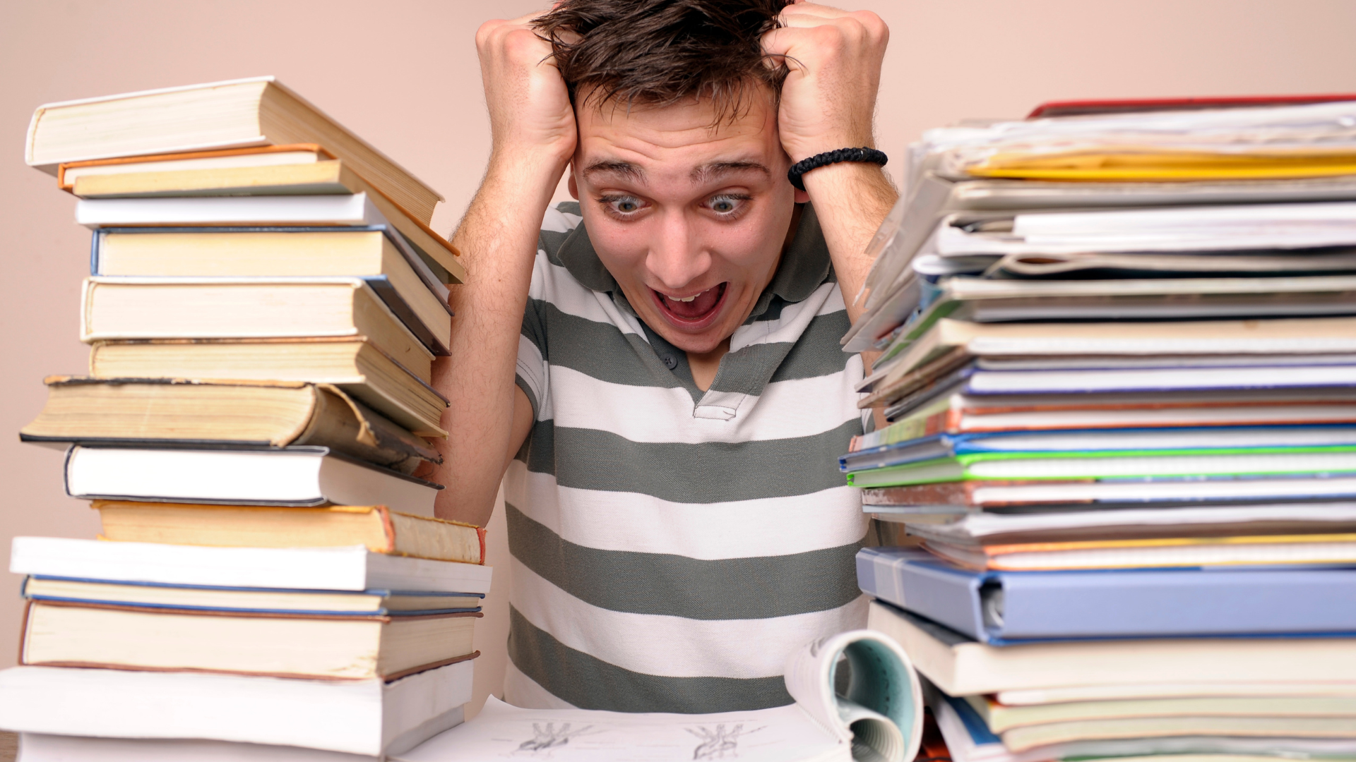 student surrounded by books with a stressed look on their face