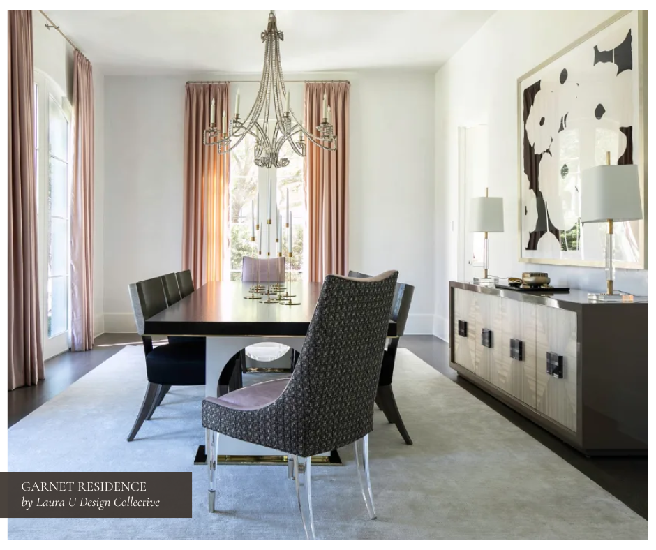 Sophisticated dining room with blush pink drapery, a sleek black dining table surrounded by contemporary seating, sculptural chandeliers, and a modern sideboard topped with white lamps and abstract black-and-white artwork.