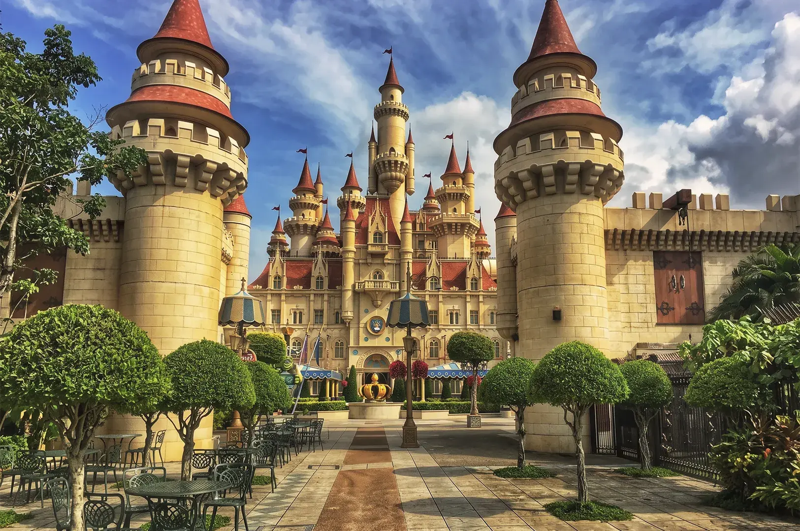 Front view of Far Far Away Castle at Universal Studios Singapore surrounded by manicured trees, outdoor seating, and fairy‑tale architecture.