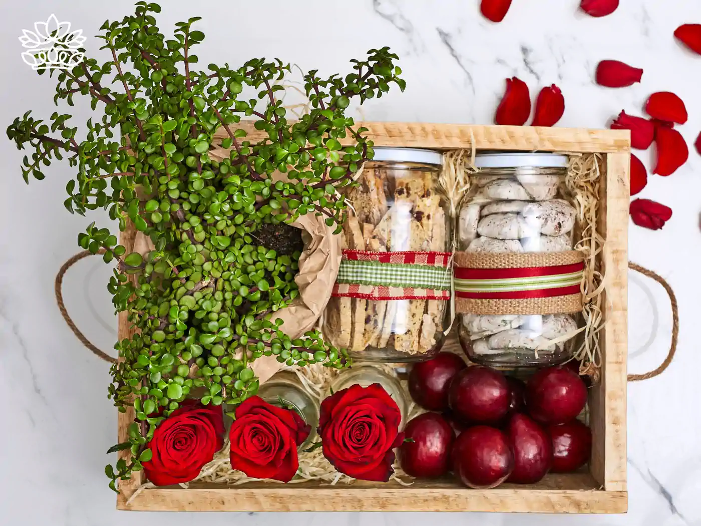 A delightful wooden gift box with jars of cookies, fresh red apples, vibrant roses, and a lush plant, offering a unique gift box for mum. Delivered with heart. Fabulous Flowers and Gifts.