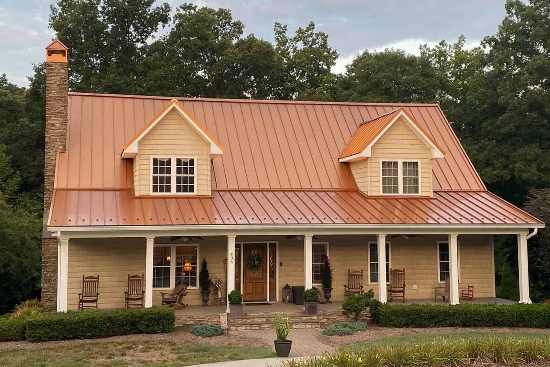 A picture of a home with a custom copper roof, to create contrast with the materials and style of the home.