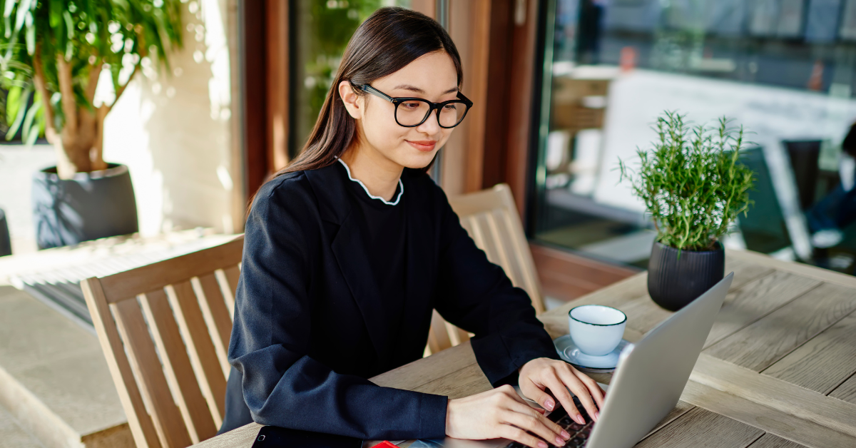 A professional woman working on her laptop outdoors, researching how to do taxes for OnlyFans efficiently.