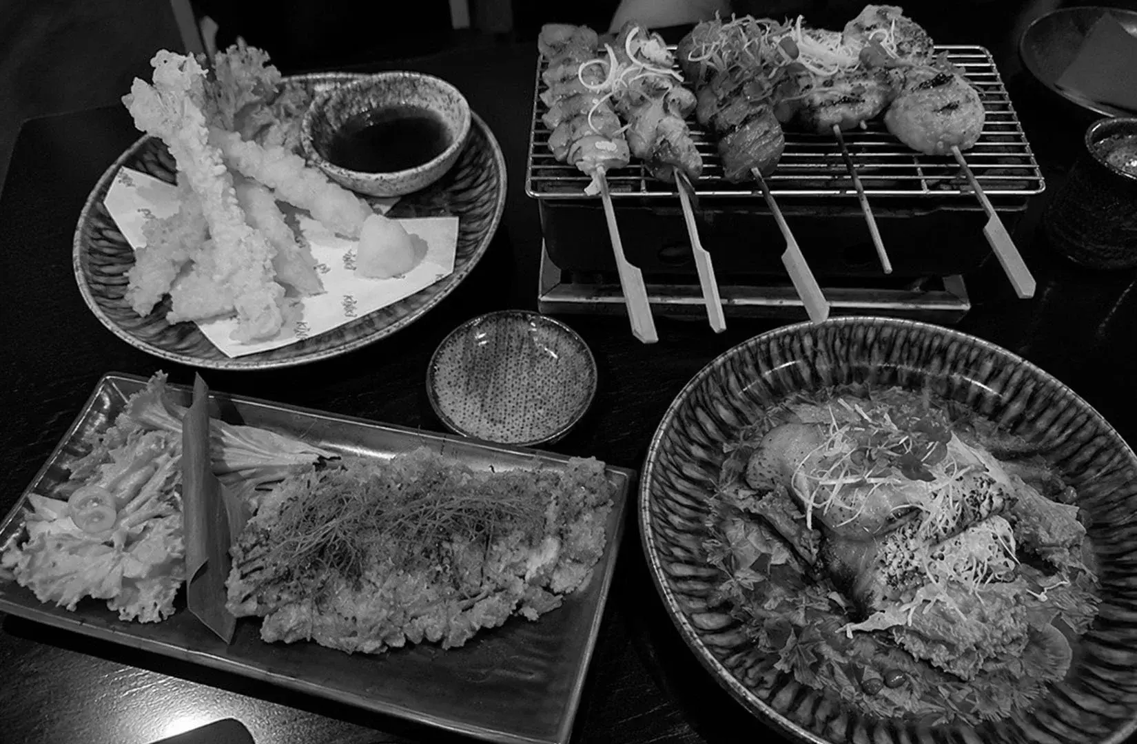 Japanese dishes featuring tempura, grilled skewers, and seafood served for sharing.