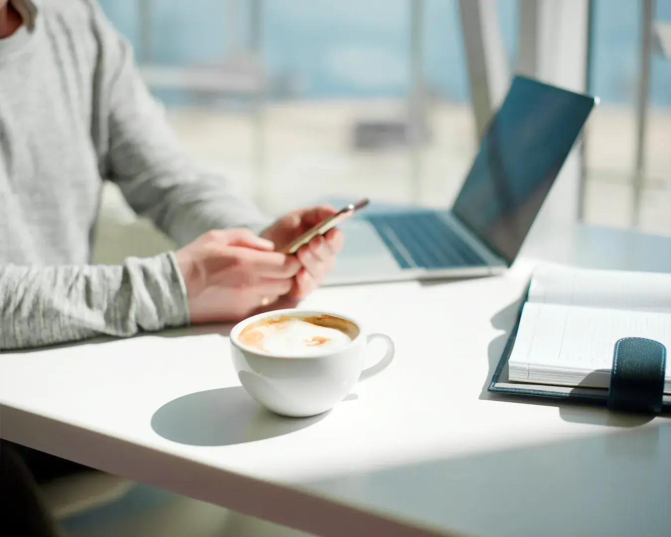 Customer checking restaurant loyalty account on mobile phone with coffee and laptop