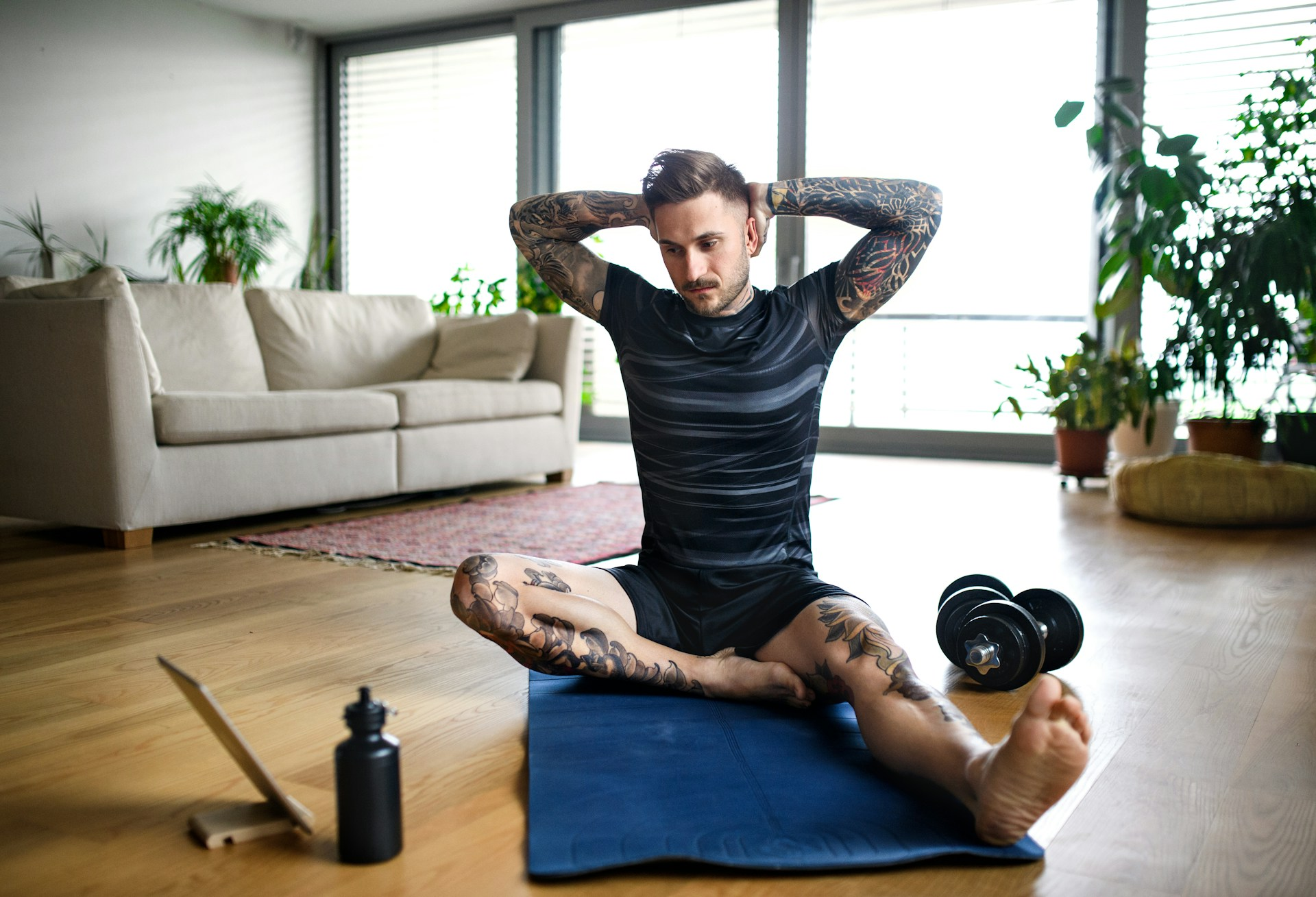 A man exercising on a yoga mat to a workout on his tablet, hoping to feel good and increase his sperm count