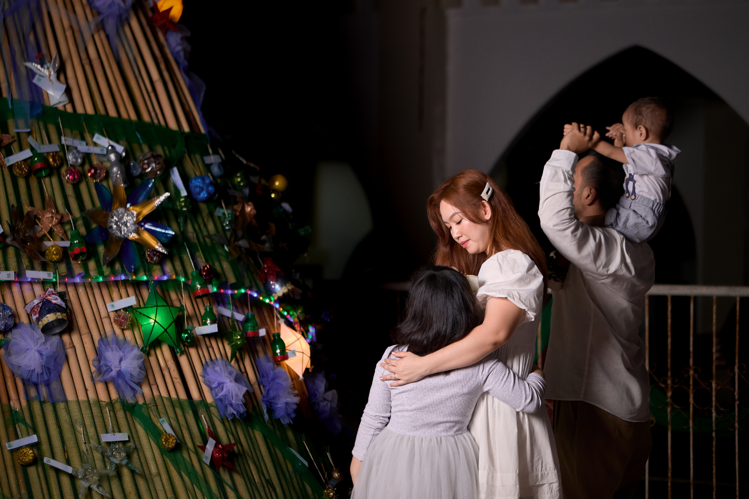 A Filipino family looking at a Christmas tree.