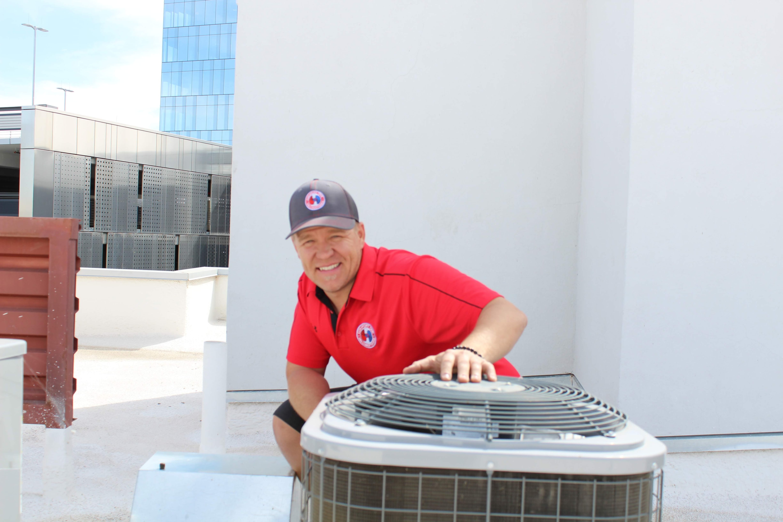 A professional HVAC technician is inspecting an outdoor AC unit on a hot summer day, checking components like the condenser coils and air filter to ensure the air conditioning system is blowing cool air effectively. The technician is focused on maintaining optimum cooling capacity and troubleshooting any potential issues that could affect indoor air quality.