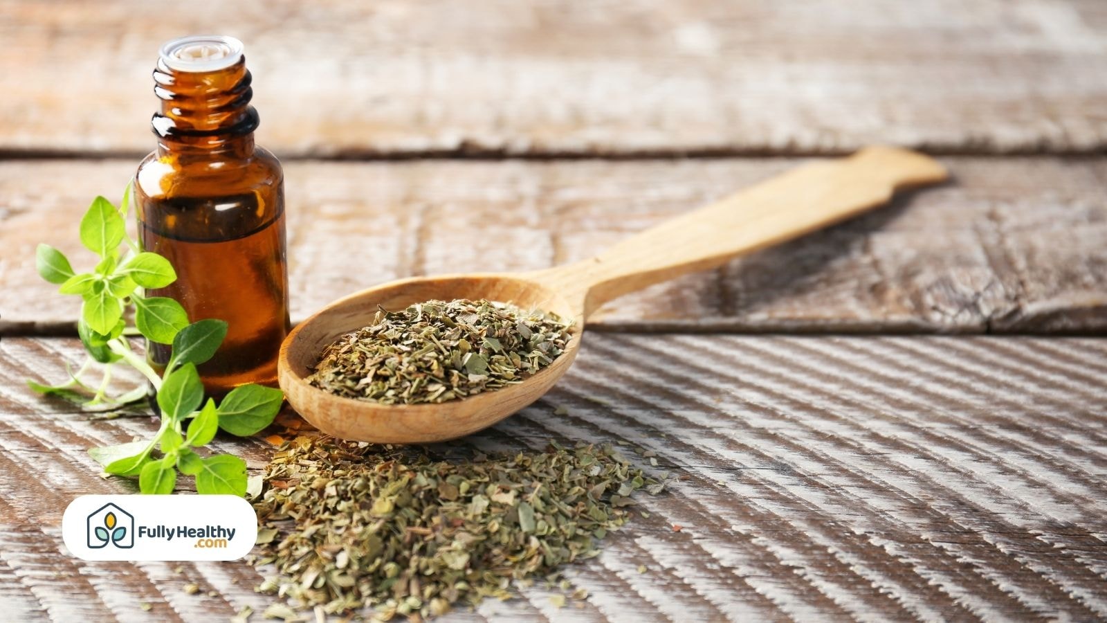 Oregano oil bottle with dried oregano on wooden spoon and table