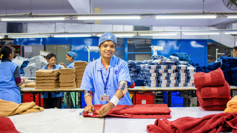 A person is working in a fabric factory with lots of towels
