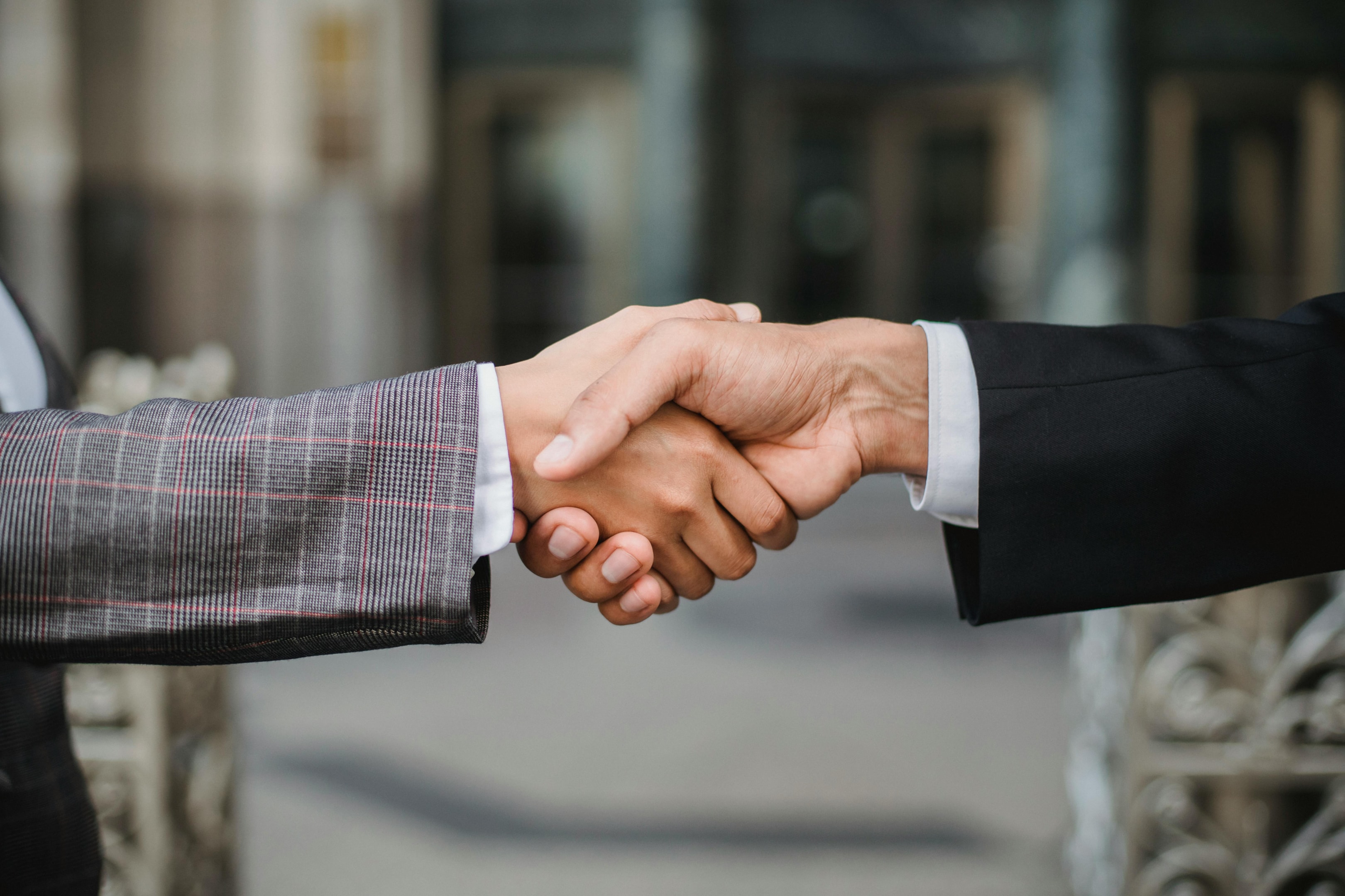 Handshake between real estate wholesaler and end buyer after successful contract assignment.