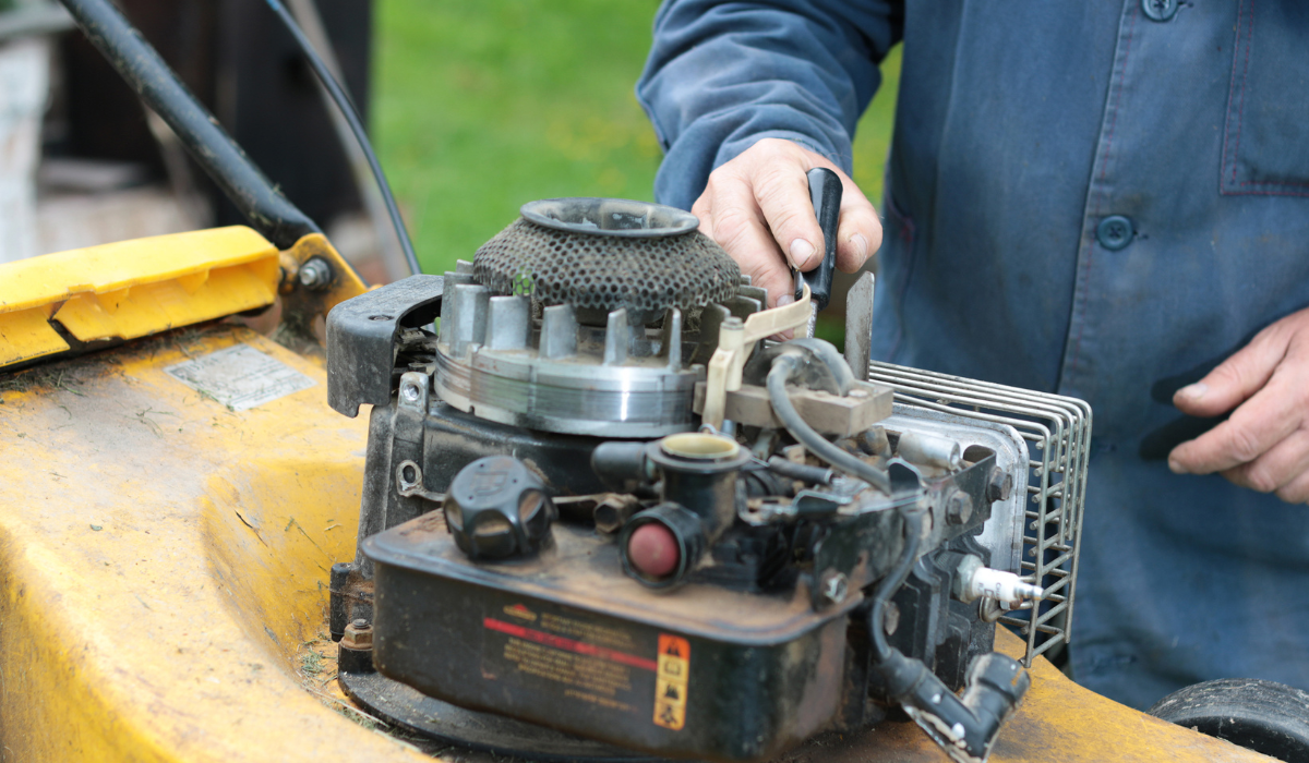A figure checking a mower engine 