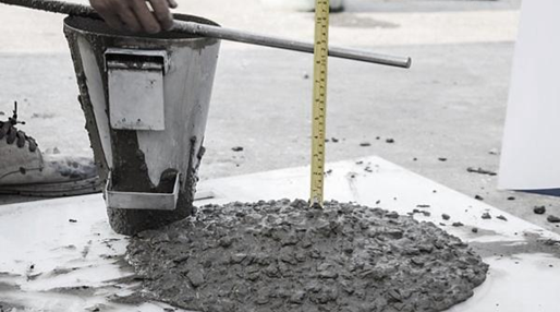 A person using a slump cone to measure the consistency of concrete mix