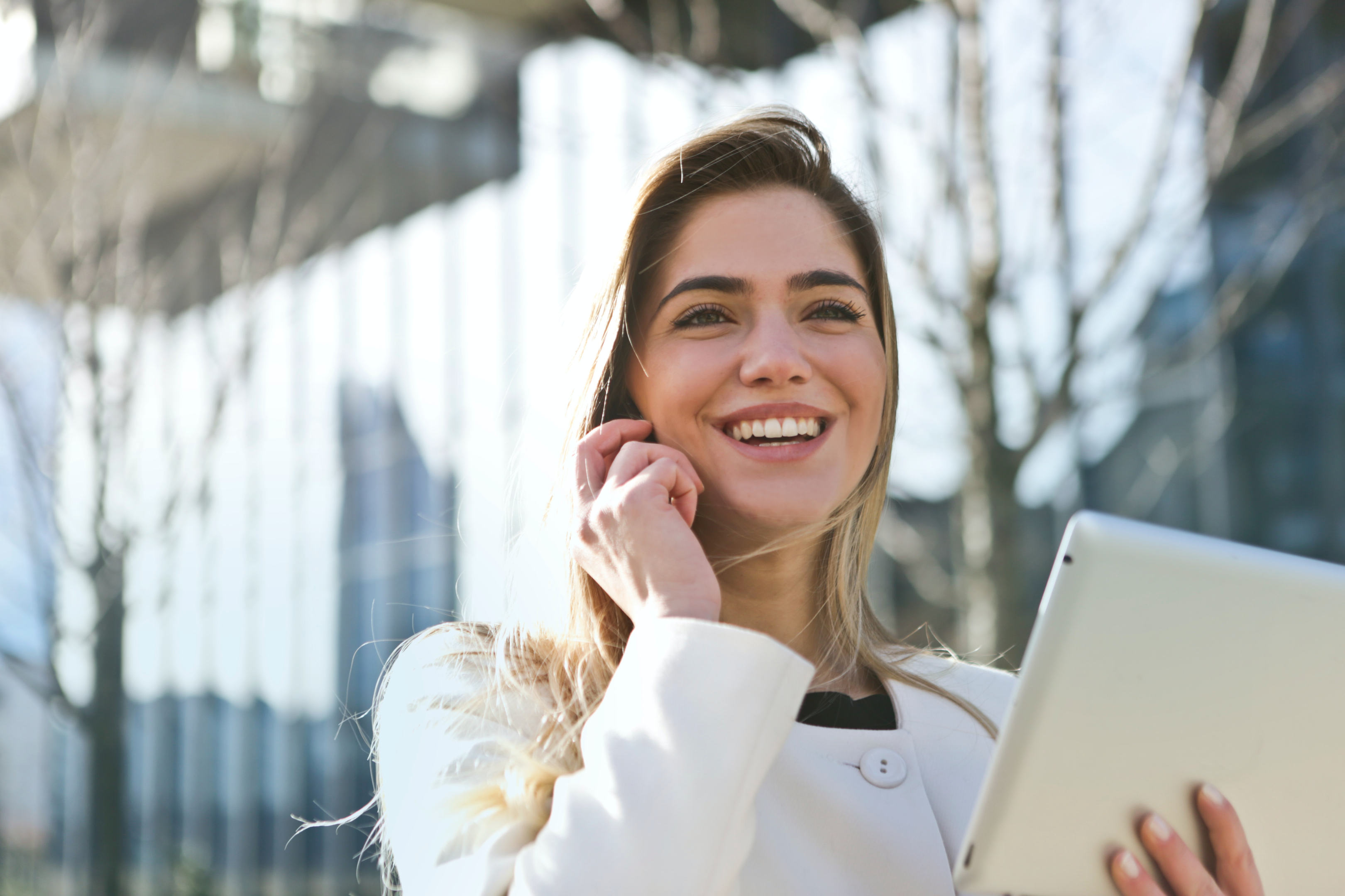 Woman smiling while using the phone and holding a tablet