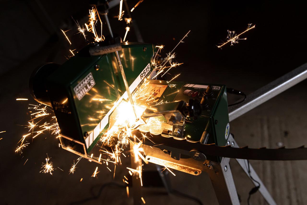 A Woodland Mills RS15 Bandsaw Blade Sharpener sharpening a blade with sparks flying.