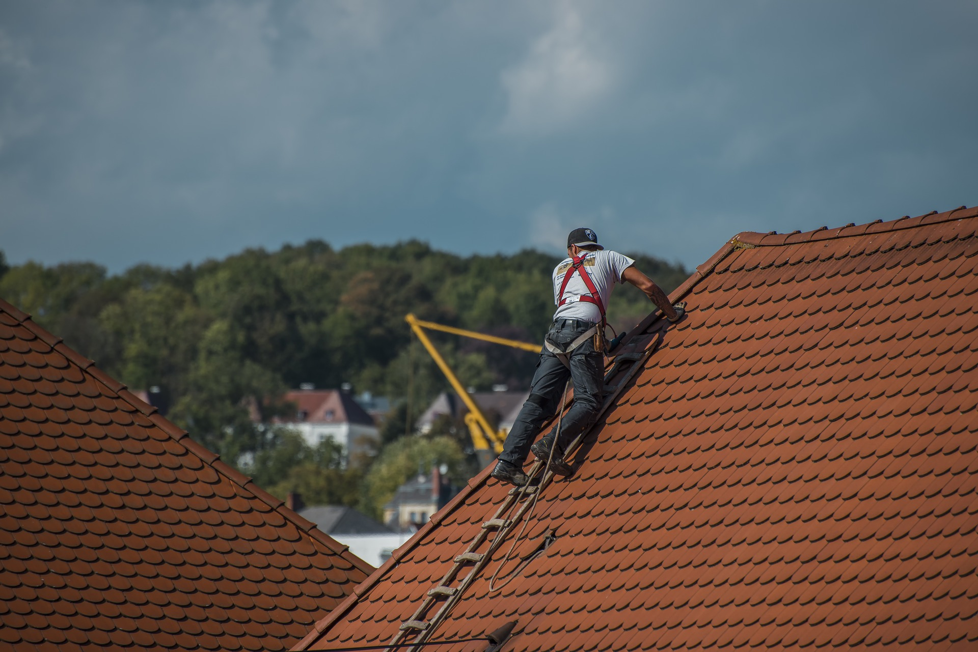 roofer climbing terra cotta tile roof