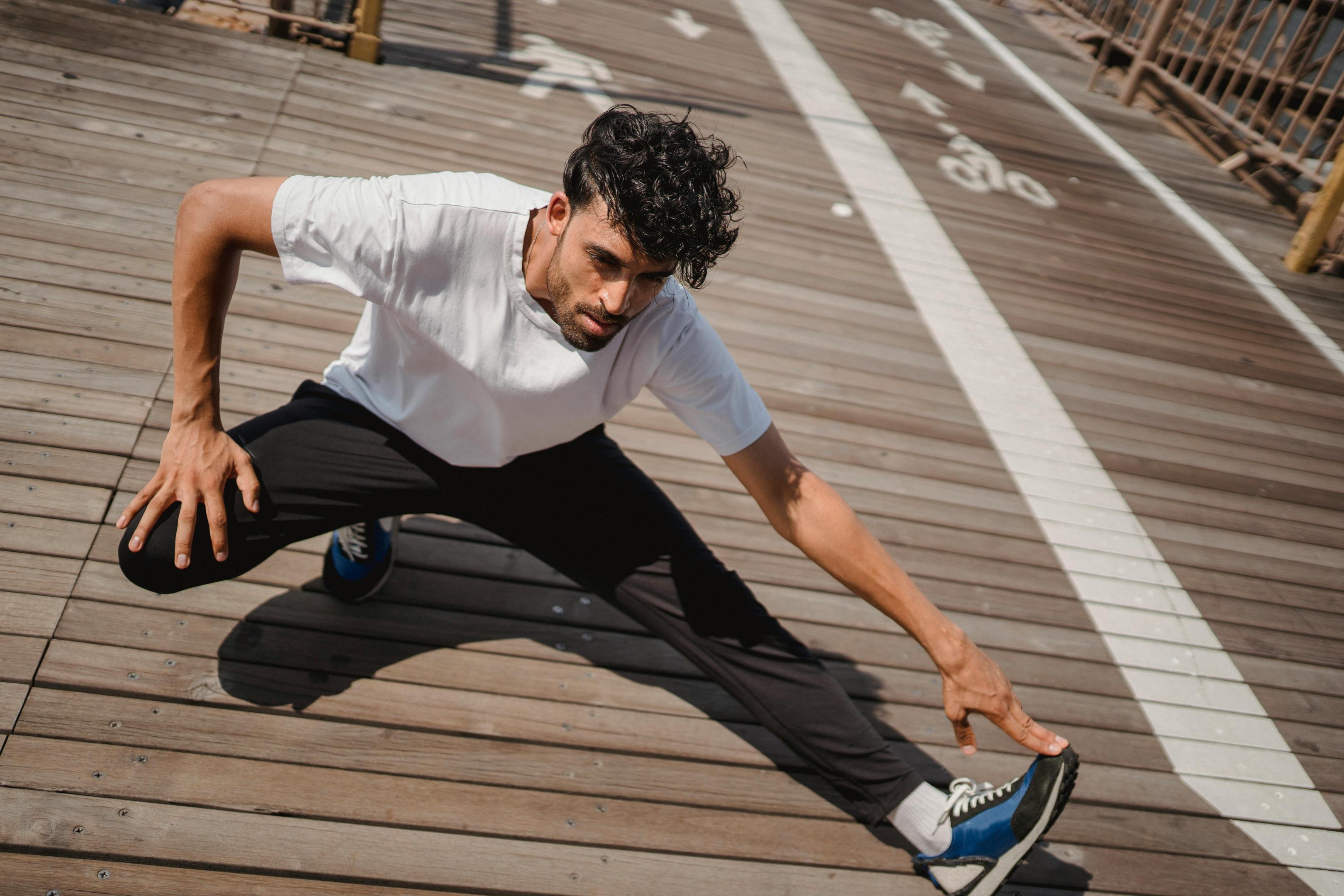 Runner doing a deep side lunge stretch on a wooden boardwalk, reaching toward the extended foot.