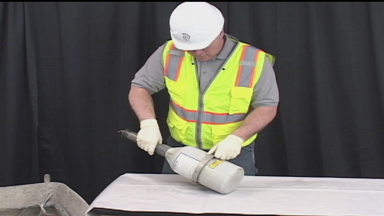 A rubber mallet being used to tamp the concrete sample in the measuring bowl
