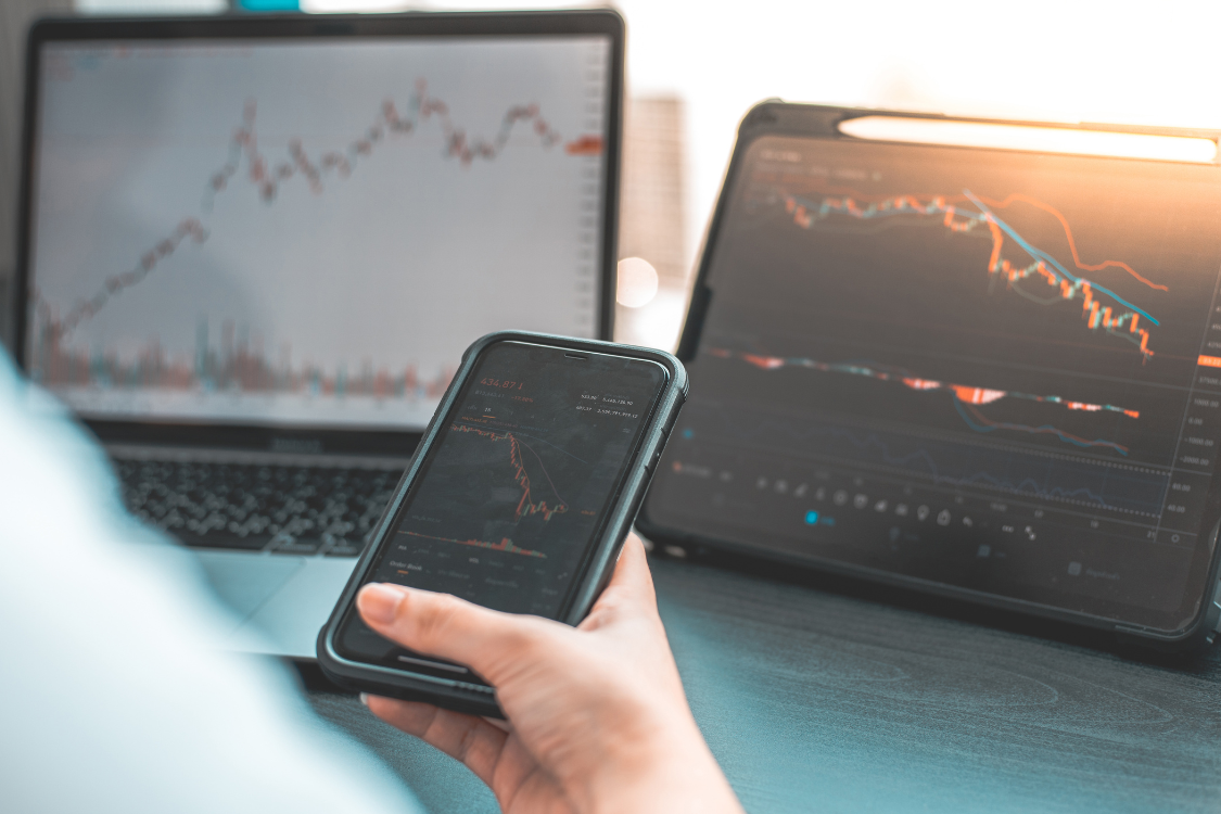Person reviewing business valuation data on multiple screens and a mobile device