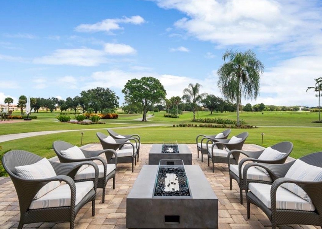 The image depicts a luxurious Mediterranean-style estate home featuring a classic tile roof and beautifully manicured landscaping, situated in the prestigious Vineyards Country Club of Naples, Florida. This elegant property embodies the natural beauty and refined architecture characteristic of the region.