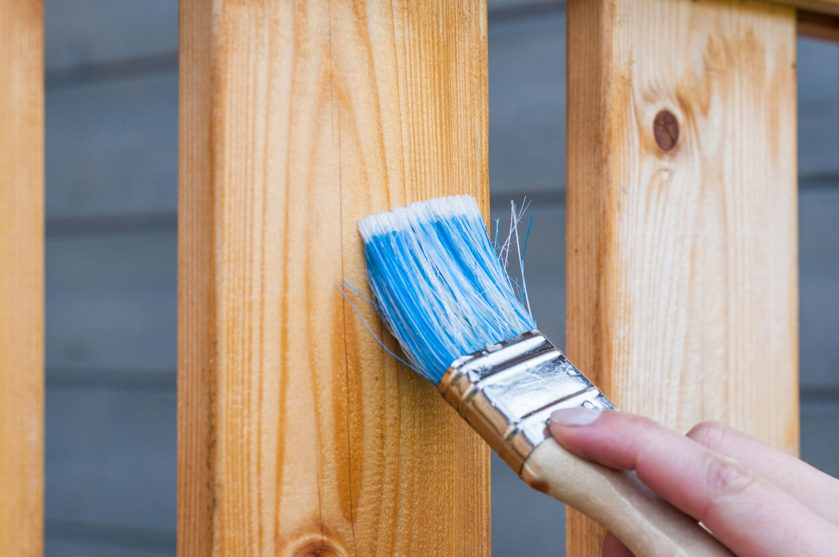 House flipper works on property, giving outdoor deck a fresh coat of paint.