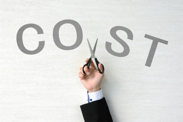 A photo of a hand of a man holding a siccor cutting the word COST