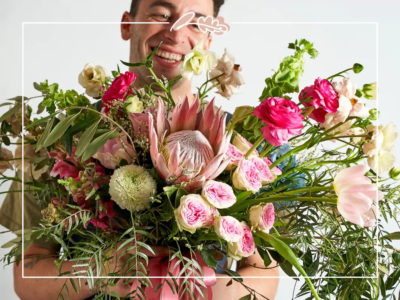 A person holding a vibrant bouquet of various flowers including pink roses and proteas. Fabulous Flowers and Gifts - Birthday Collection.