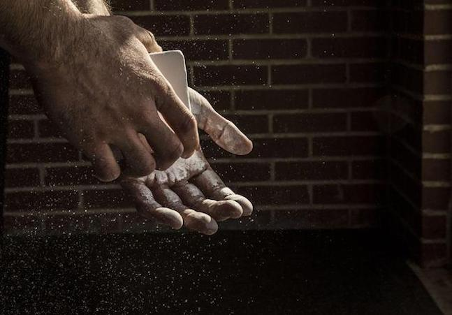 A person applying chalk to their hands to improve grip