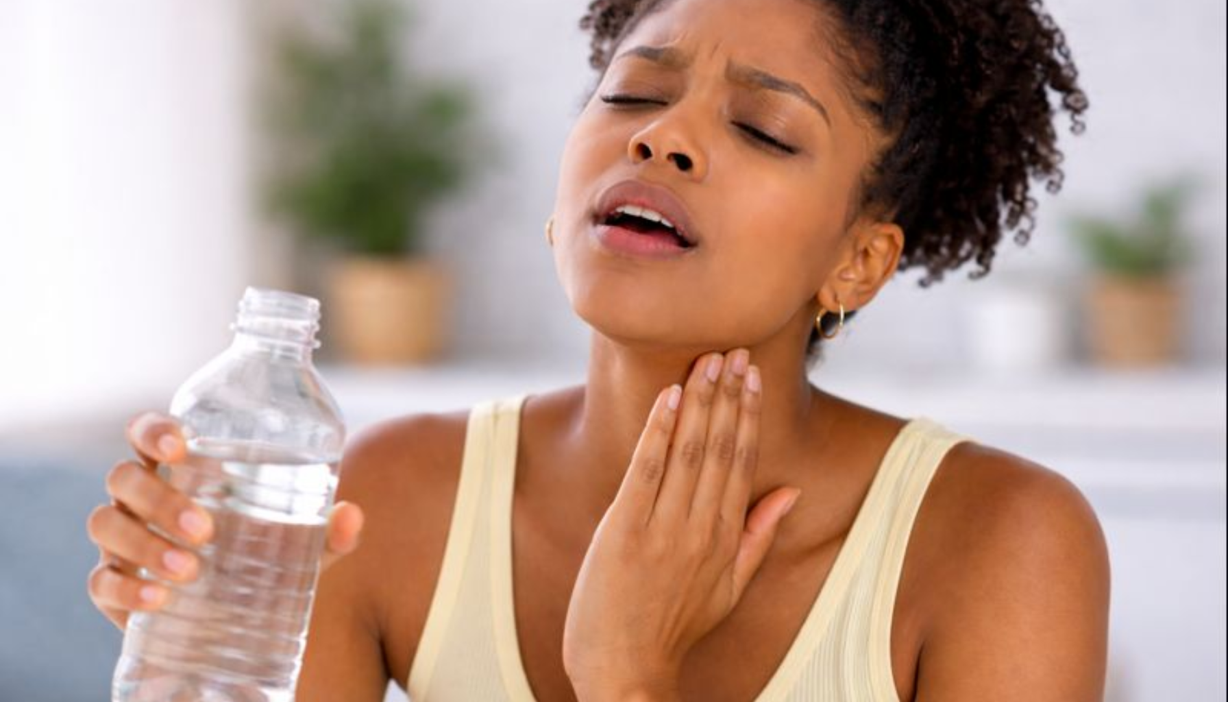 Tørr i Halsen: Når Problemet Starter i Munnen 15 Kvinne med tørr hals holder vannflaske, viser ubehag som kan starte i munnhulen.