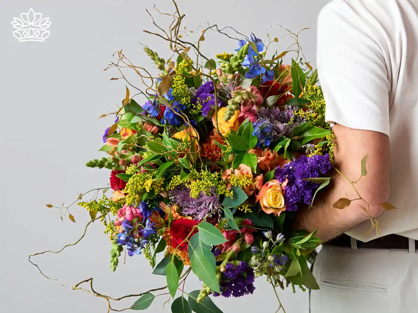 A man holding a lush and colorful bouquet of get well flowers featuring vivid blues, purples, and oranges, intertwined with natural greenery. Delivered with Heart. Fabulous Flowers and Gifts.