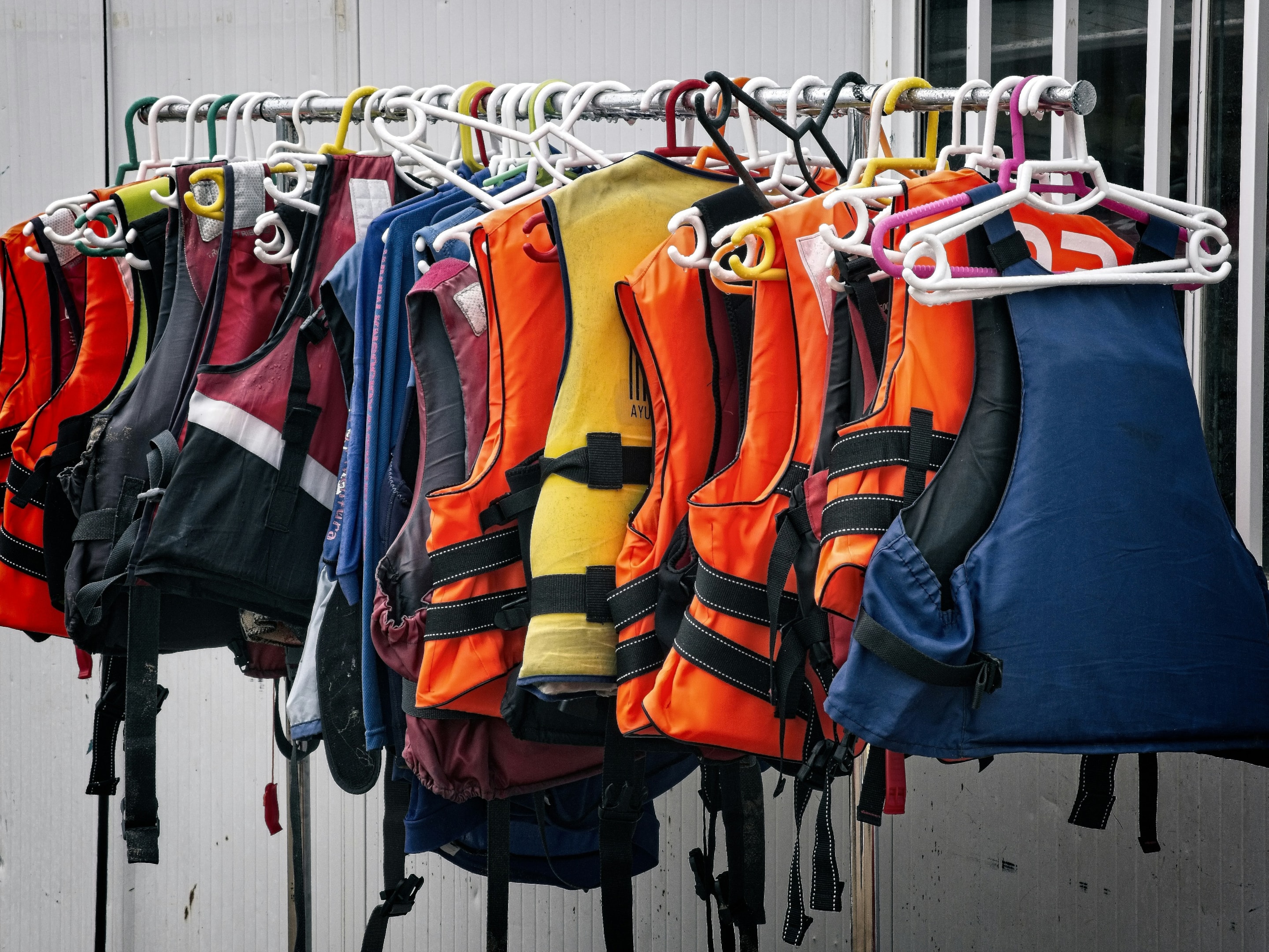 An assortment of life vest types displayed on a rack.