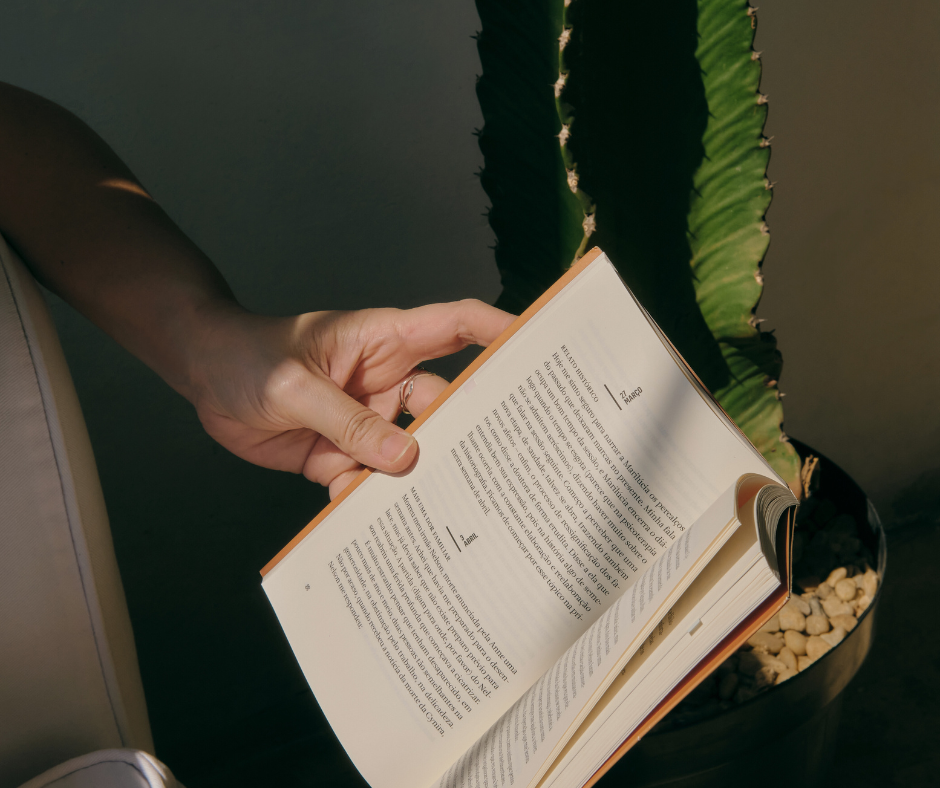 a woman reading a book by a cactus