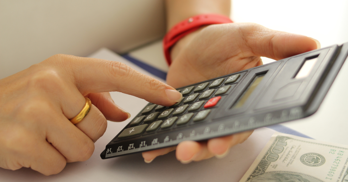 Person holding a calculator beside U.S. dollar bills, representing how to calculate FICA tax accurately.