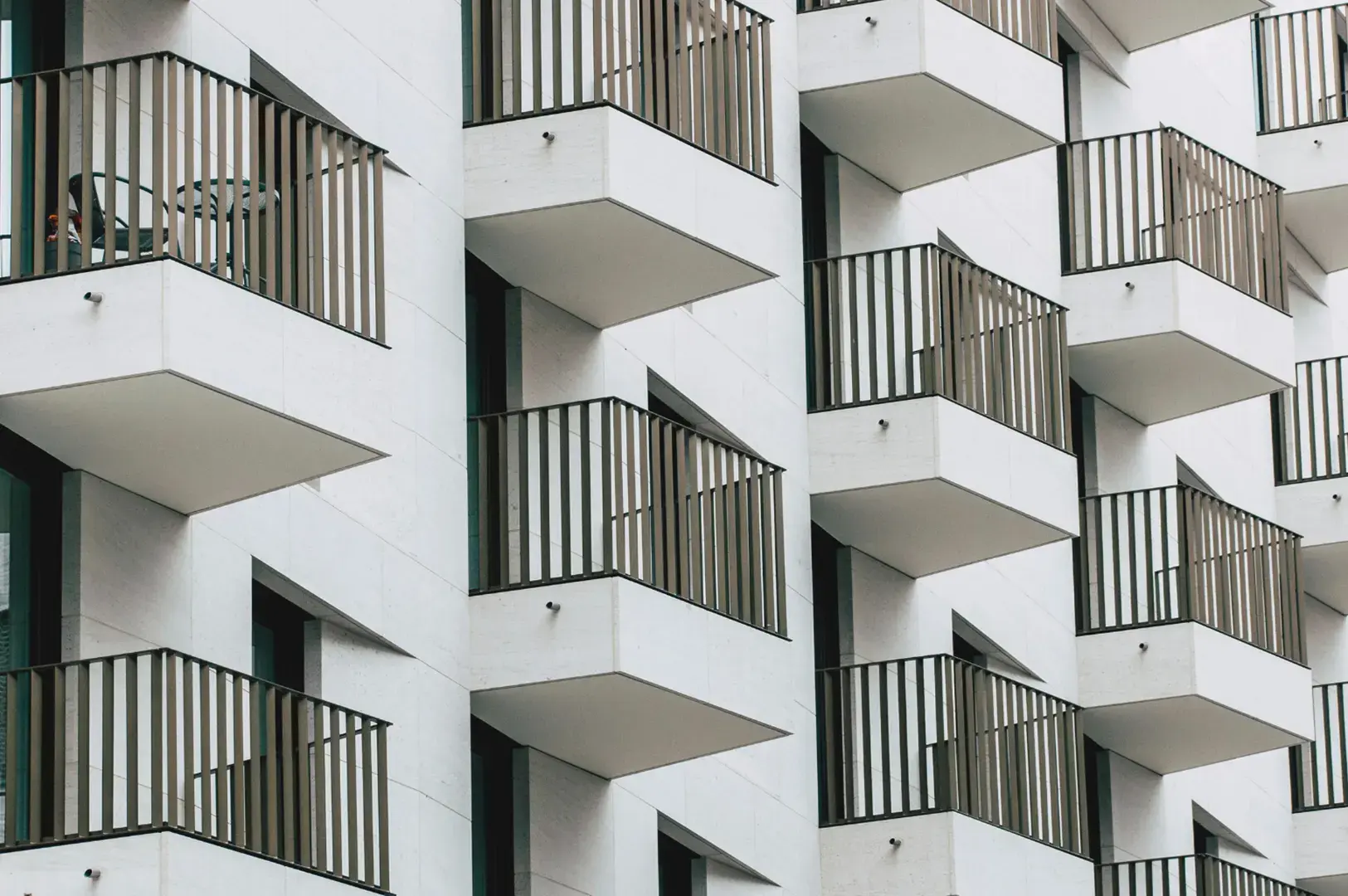 A modern building facade with repeating balconies and dark railings.