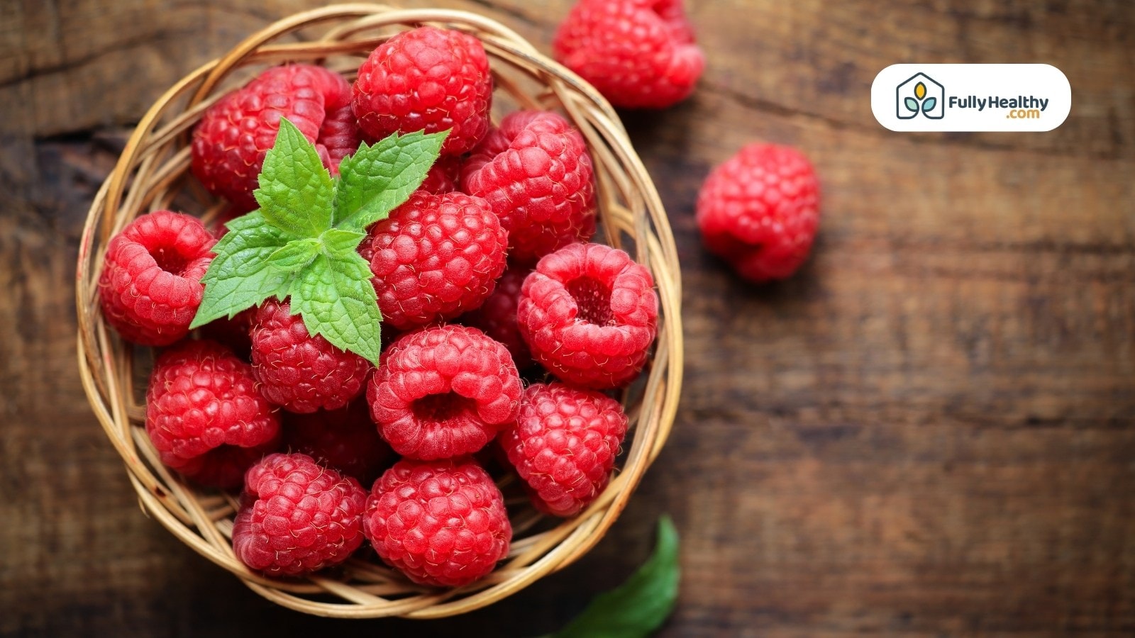 Raspberries in a wicker basket garnished with fresh mint leaves