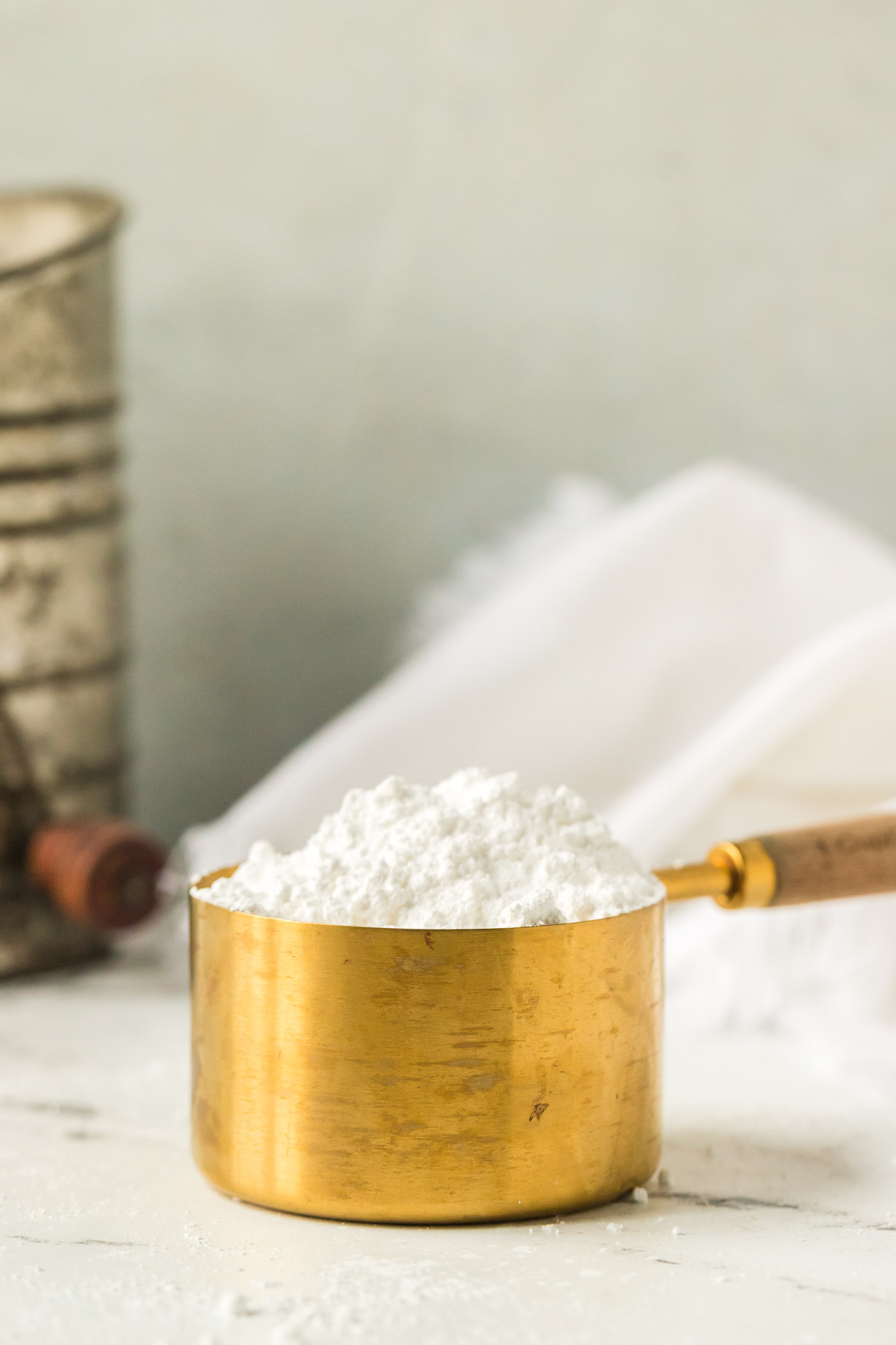 gold measuring cup of powdered sugar