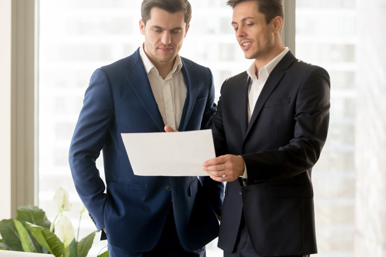 A person in a suit holding a folder while standing in a living room.