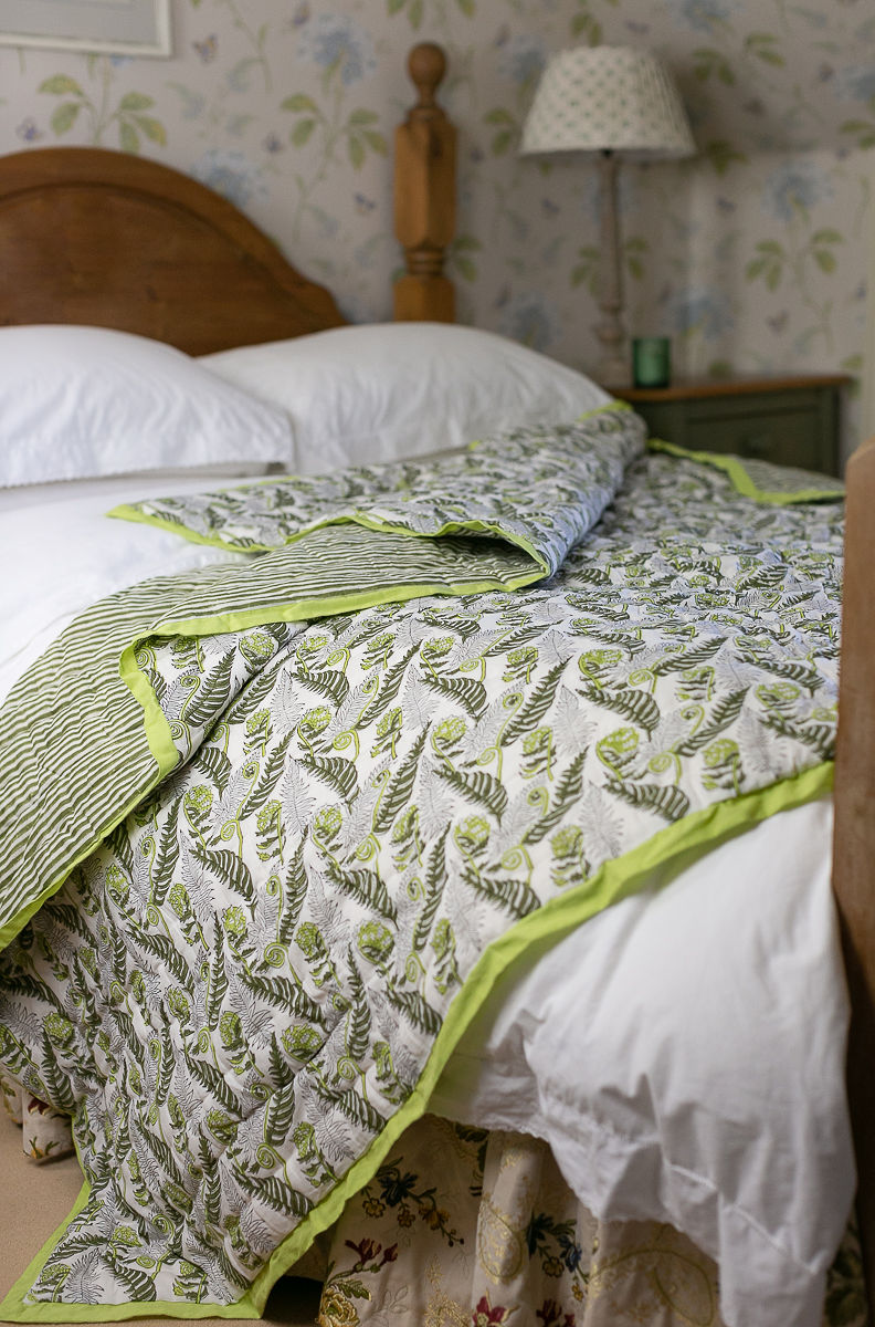 Bed made up with a handblock pinted quilt in the golden fern design 