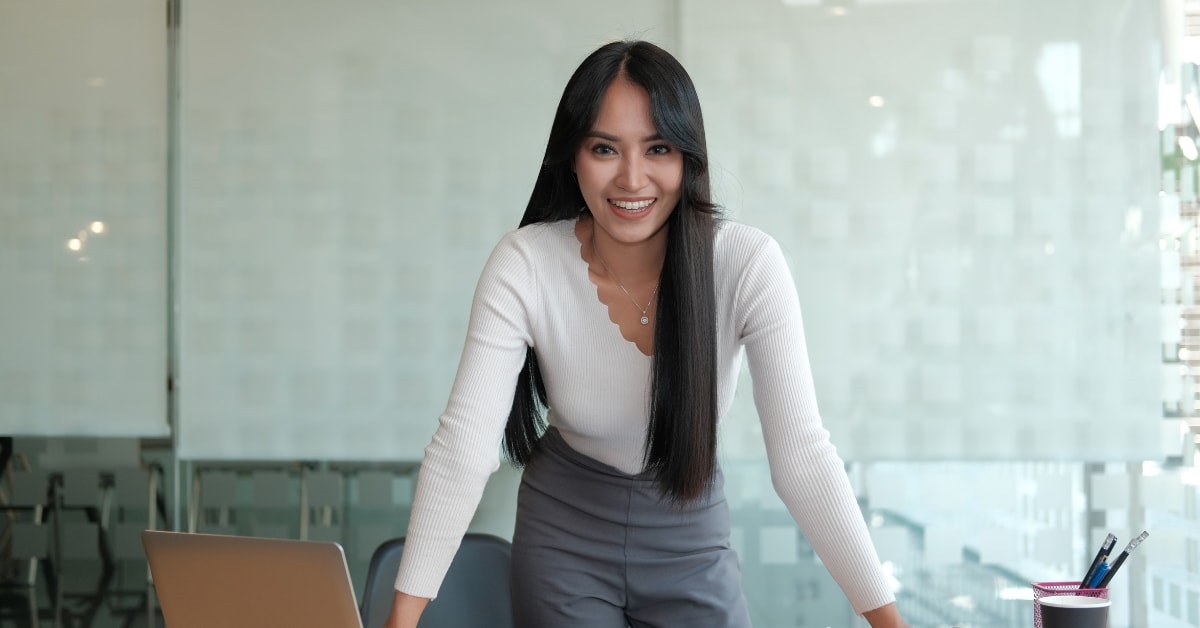 A smiling OnlyFans personal tax advisor standing confidently at her desk in a modern office.