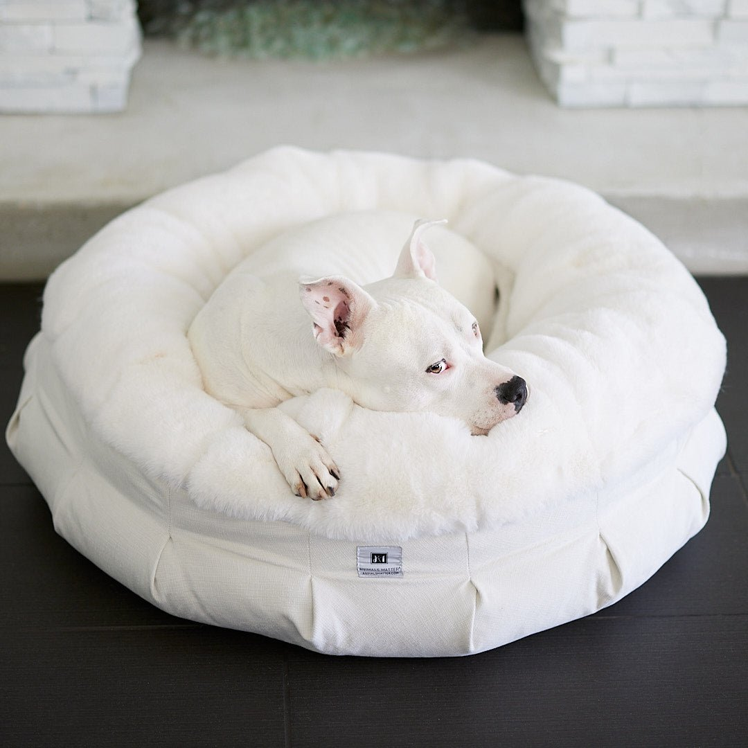 A white donut dog bed with a plush cushioning and a high bolster design