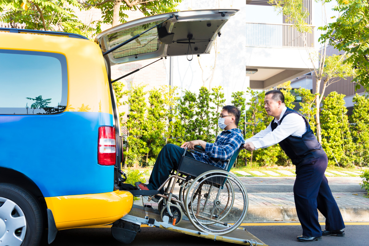 A taxi driver transports man in wheelchair into taxi