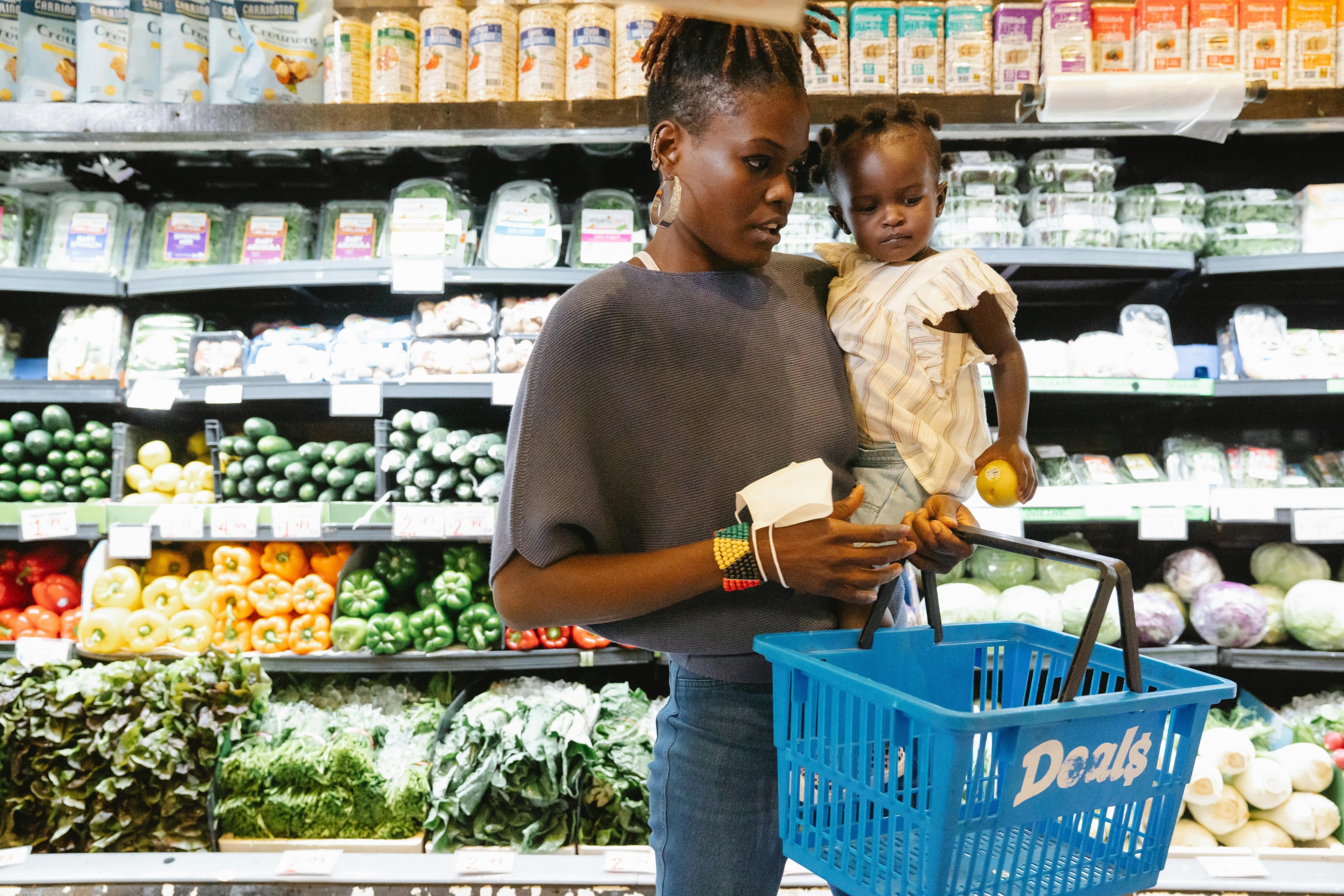 Photo by Greta Hoffman : https://www.pexels.com/photo/a-mother-carrying-her-daughter-and-shopping-basket-9706141/