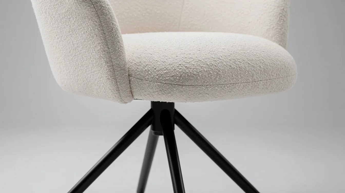 Close-up van een draaibare eetkamerstoel bekleed met bouclé stof, die rust op een metalen spinpoot. Deze stijlvolle keuze biedt extra comfort en een moderne uitstraling, perfect voor gezellige avonden rond de eettafel.