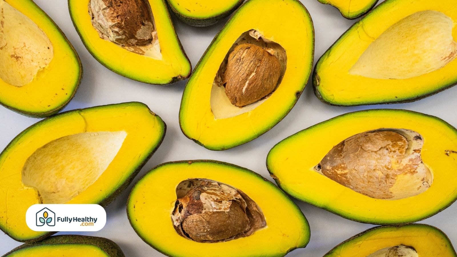 Multiple ripe avocado halves with visible seeds and yellow flesh